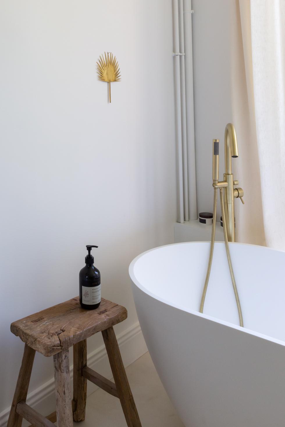 Badewanne mit Messingarmaturen und gewachstem Betonboden